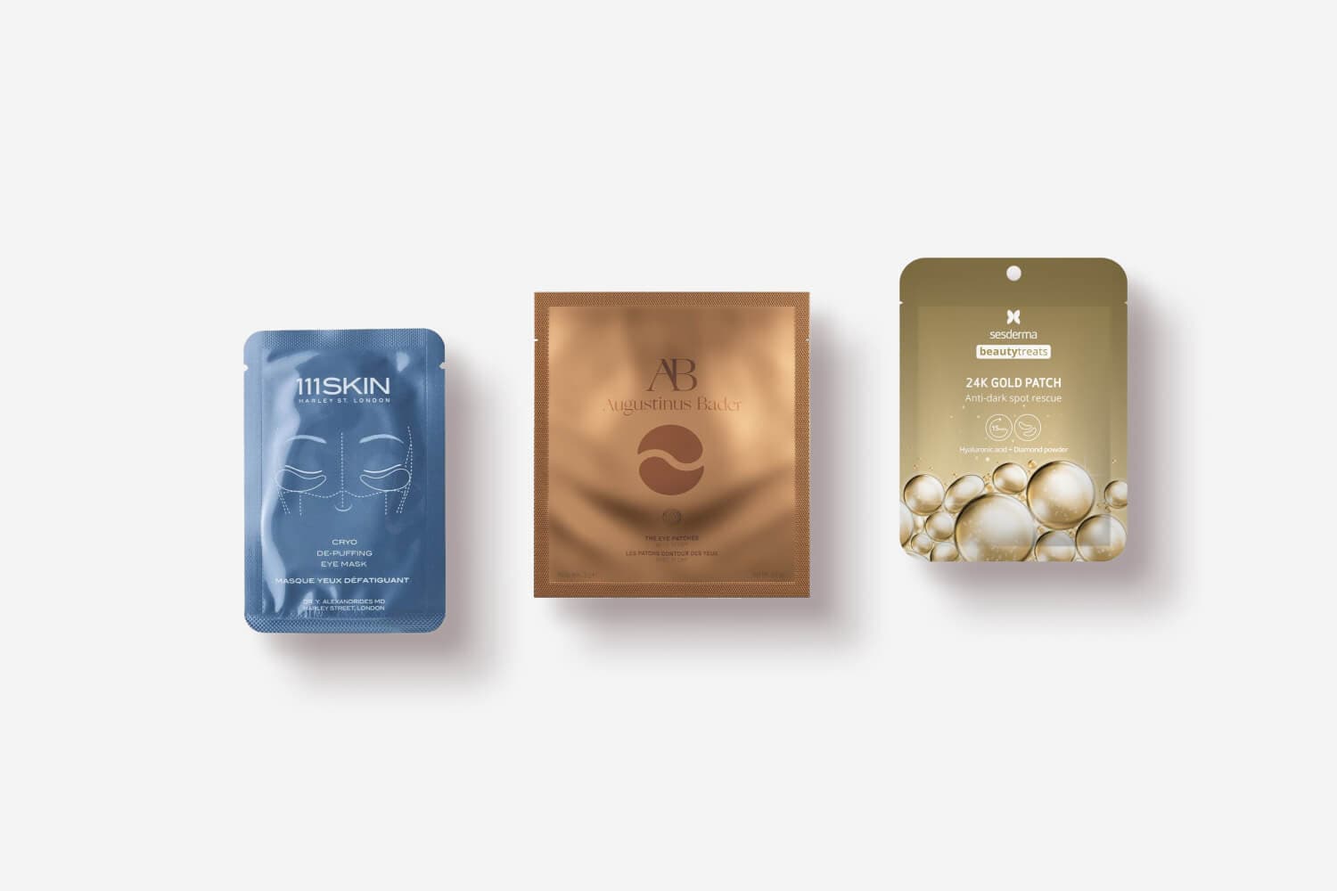 111SKIN Cryo De-Puffing Eye Mask, Augustinus Bader The Eye Patches and Sesderma Beauty Treats 24K Gold Patch sachets in a row