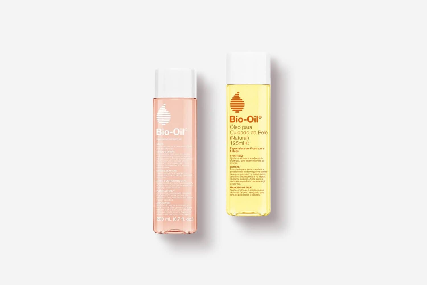 Two Bio-Oil bottles side by side: pink Specialist Skincare Oil 200 mL and yellow Óleo para Cuidado da Pele Natural 125 ml.
